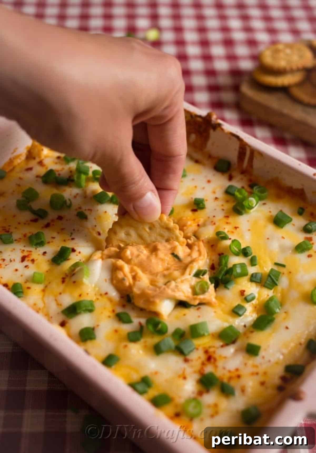 Quick & Creamy Buffalo Chicken Dip 2 Warm and creamy Easy Buffalo Chicken Dip being served with a butter cracker for dipping