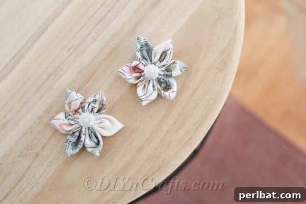 A pair of elegant fabric flowers resting on a wooden table, highlighting their delicate textures.