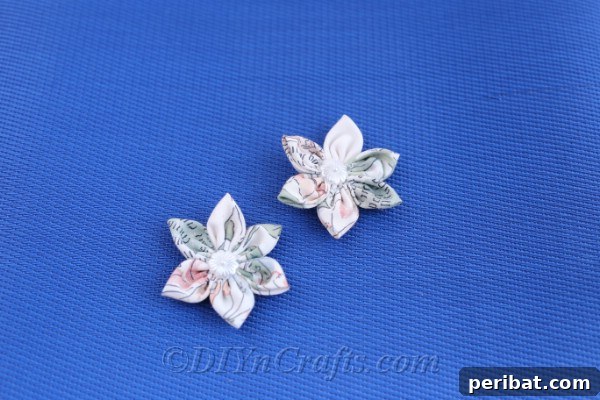 Two charming fabric flowers presented against a soft blue backdrop, emphasizing their vibrant colors.