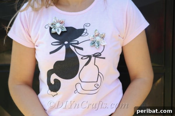 Two exquisite fabric flowers delicately pinned to a worn t-shirt, demonstrating their stylish versatility.