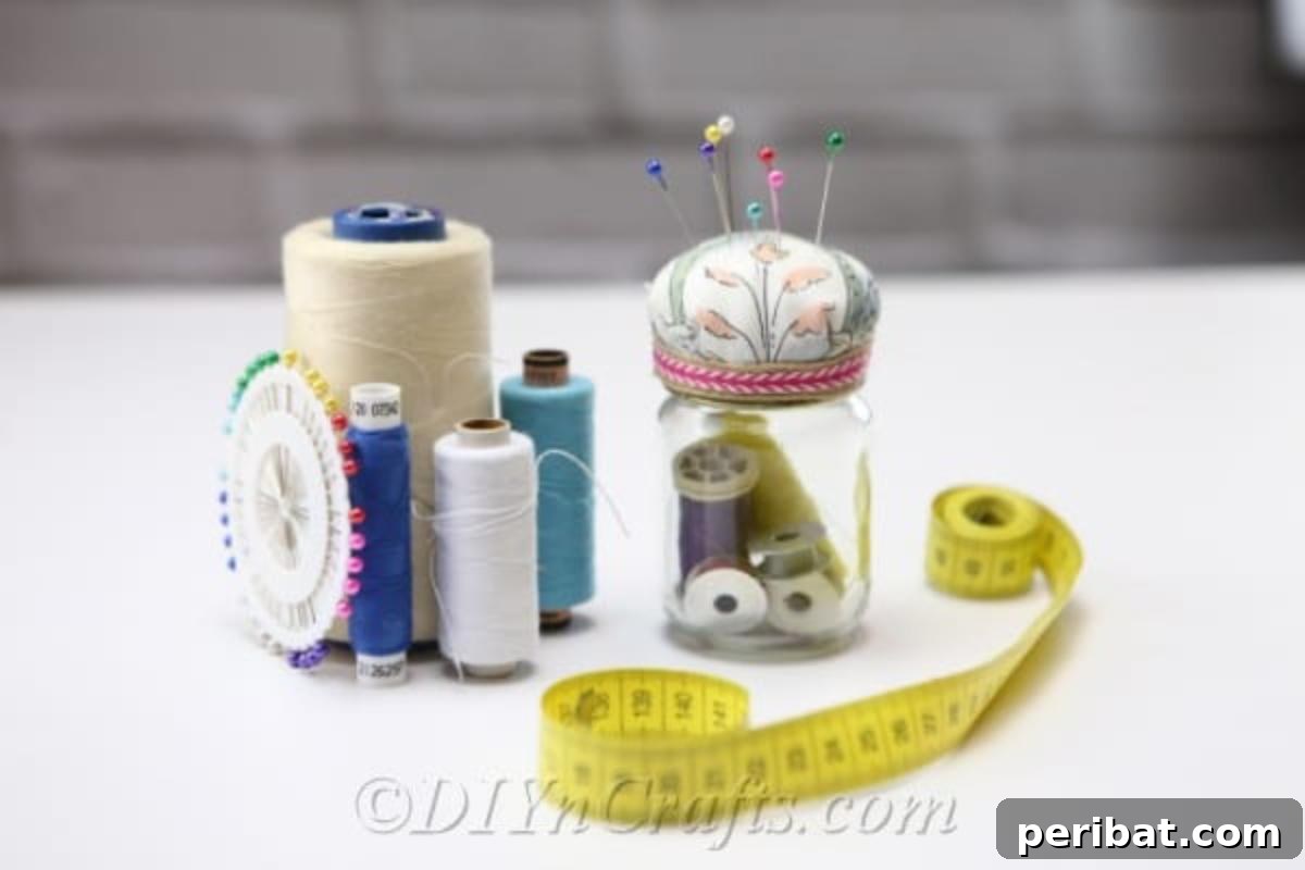 Clever Pincushion Jar Sewing Caddy 2 A vibrant DIY pincushion jar displayed with spools of thread and fabric swatches, ready for a sewing project.