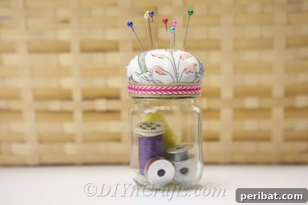 Clever Pincushion Jar Sewing Caddy 20 A charming pincushion jar with its fabric top visible, positioned against a blurred background of a wicker basket, emphasizing its rustic appeal.