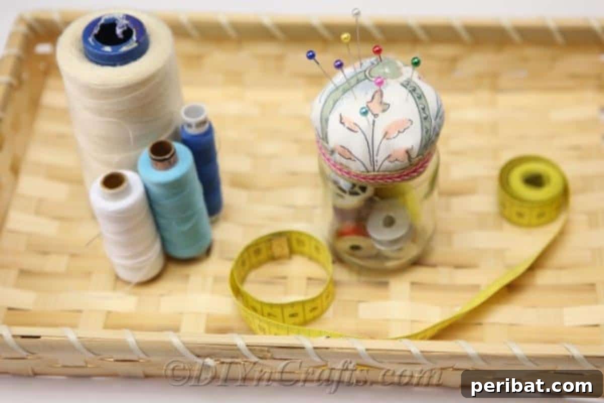 Clever Pincushion Jar Sewing Caddy 4 A completed DIY pincushion jar showcasing a cheerful fabric top, surrounded by neatly arranged sewing supplies in a rustic basket.
