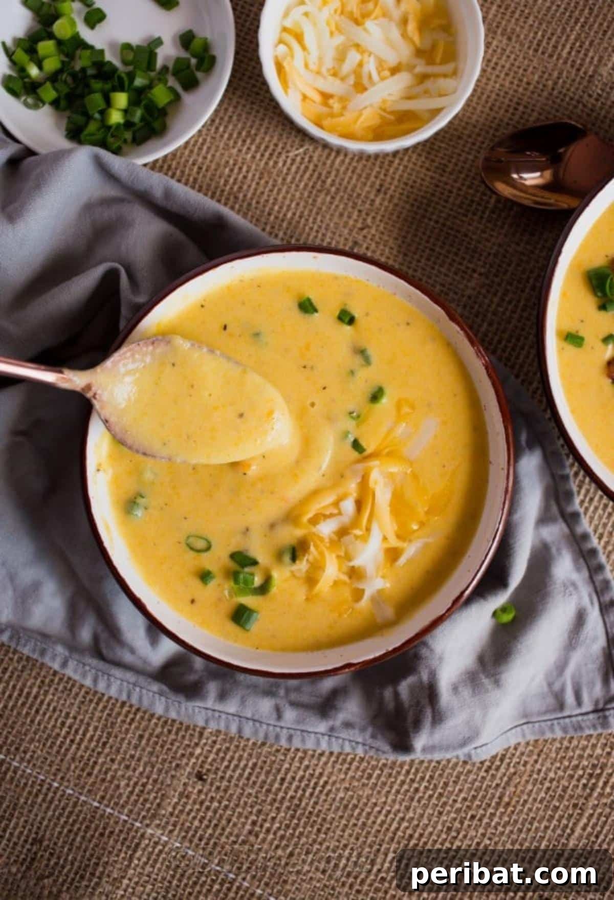 Heartwarming Cheesy Potato Comfort Soup 2 Large bowl of creamy cheesy potato soup being stirred by a spoon, showcasing its rich texture, ready to be enjoyed.