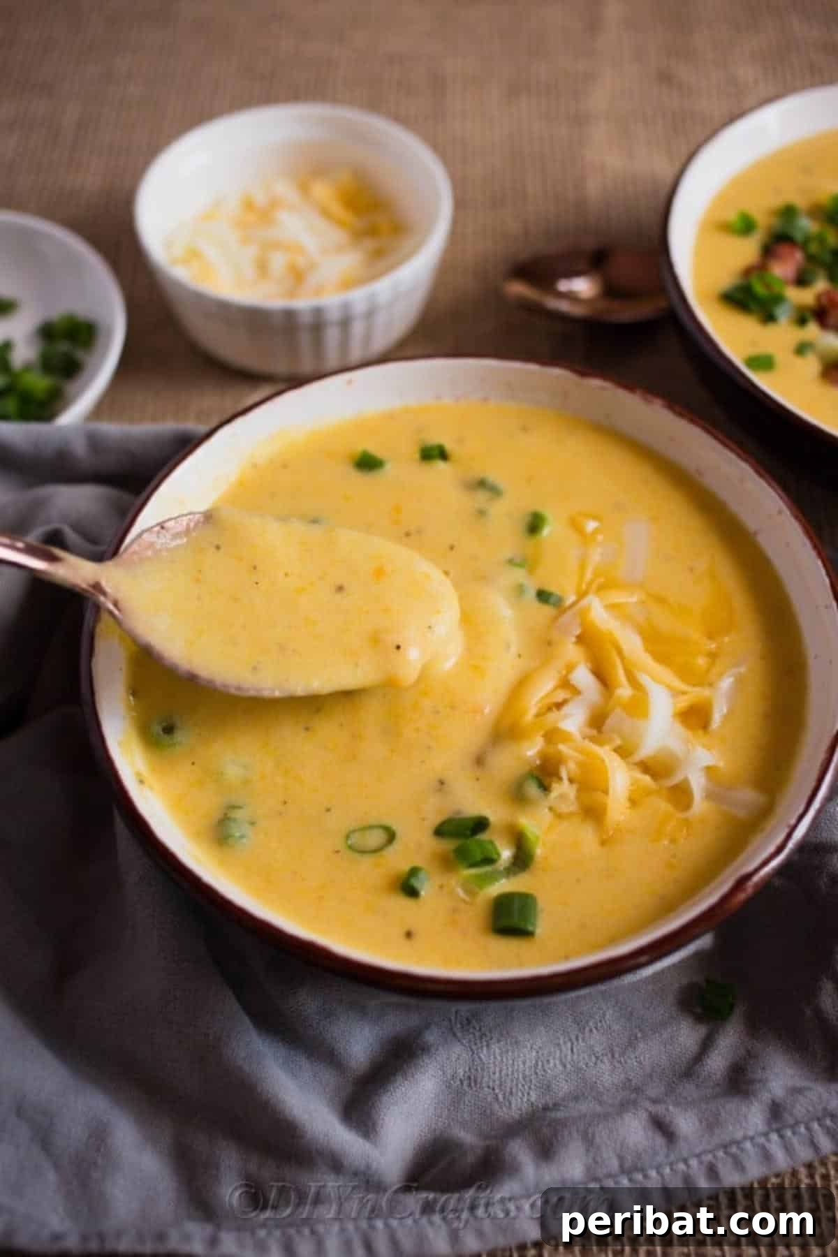 Heartwarming Cheesy Potato Comfort Soup 4 A hand stirring a bowl of rich and creamy cheesy potato soup, emphasizing its thick and inviting consistency.