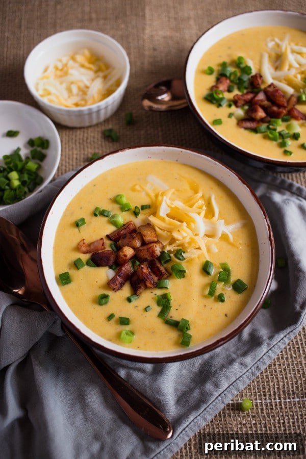 A close-up of a steaming bowl of Cheesy Potato Soup, garnished with fresh herbs and cheese, highlighting its inviting texture.