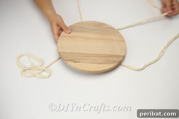 Set the slab of wood down on top of the four strands you have made, preparing to secure it for hanging.
