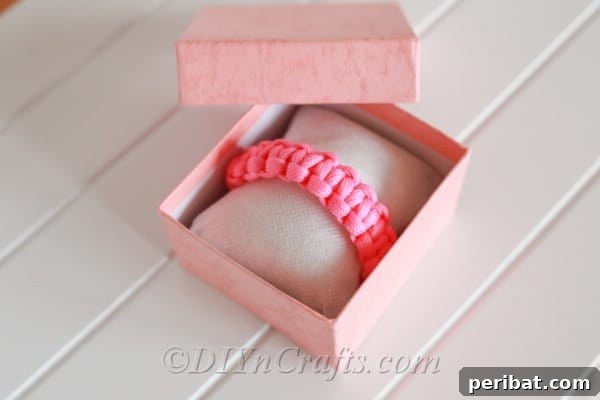 Create Your Own Square Knot Friendship Bracelet 20 A finished pink square knot bracelet friendship bracelet sitting in a pink and white jewlery box that is sitting on a white surface