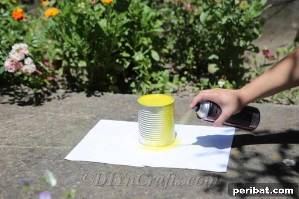 DIY Whimsical Hanging Garden Bees 7 Tin can being sprayed yellow for bee craft outside on a white piece of paper