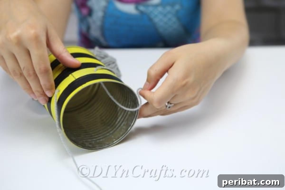 DIY Whimsical Hanging Garden Bees 9 A picture showing a woman threading twine through holes to create legs on bee craft