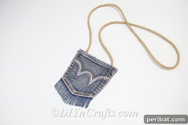 Finished denim bag with elegant pearl embellishment resting on a clean white table, ready for use.