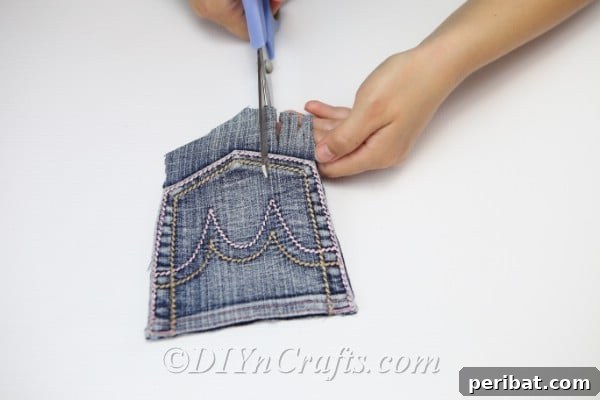 Craft Your Own Chic Denim Bag 17 Close-up of cutting a fringe on the bottom of the denim pocket for the bag, adding texture.