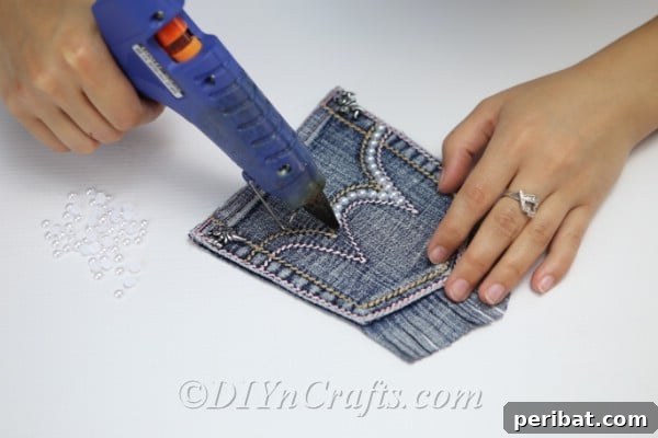 Craft Your Own Chic Denim Bag 19 Detailed view of gluing fake pearls along the seams on the pocket of the denim bag for a chic look.