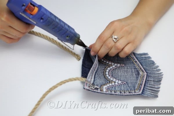 Craft Your Own Chic Denim Bag 21 Close-up of gluing a sturdy rope handle onto the DIY denim bag for durable attachment.