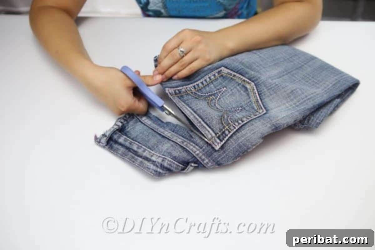 Craft Your Own Chic Denim Bag 9 Woman meticulously cutting the pockets out of a pair of blue jeans, leaving ample fabric for the denim bag project.
