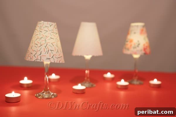 Upcycled Wine Glass Tealight Lanterns 12 Three completed diy wine glass lantern tealight candle holders sitting on an orange table surrounded by lit candles