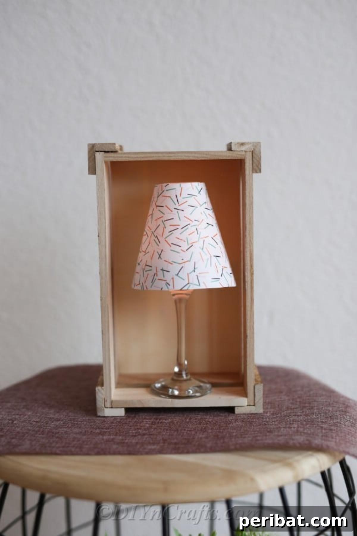 Upcycled Wine Glass Tealight Lanterns 3 A prepared tealight candle holders paper wine glass lantern on a wooden stool with lamp sitting inside a decorative wooden box