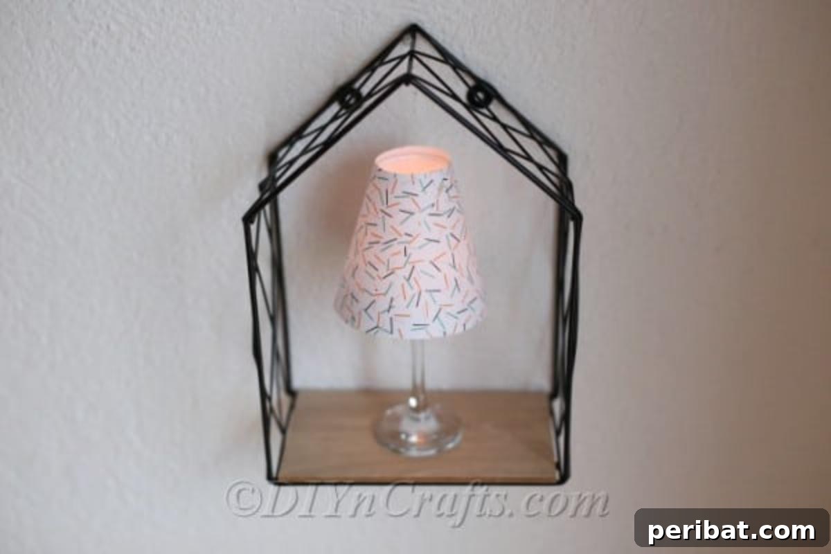 Upcycled Wine Glass Tealight Lanterns 5 Decorative wine glass lantern sitting inside a wire frame box that is attached to a wall