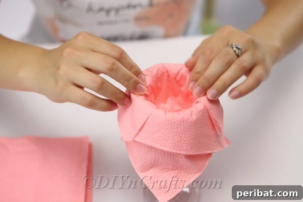 Fold Beautiful Napkin Roses 11 Overlapping pink napkins on edge of glass during how to fold napkins tutorial