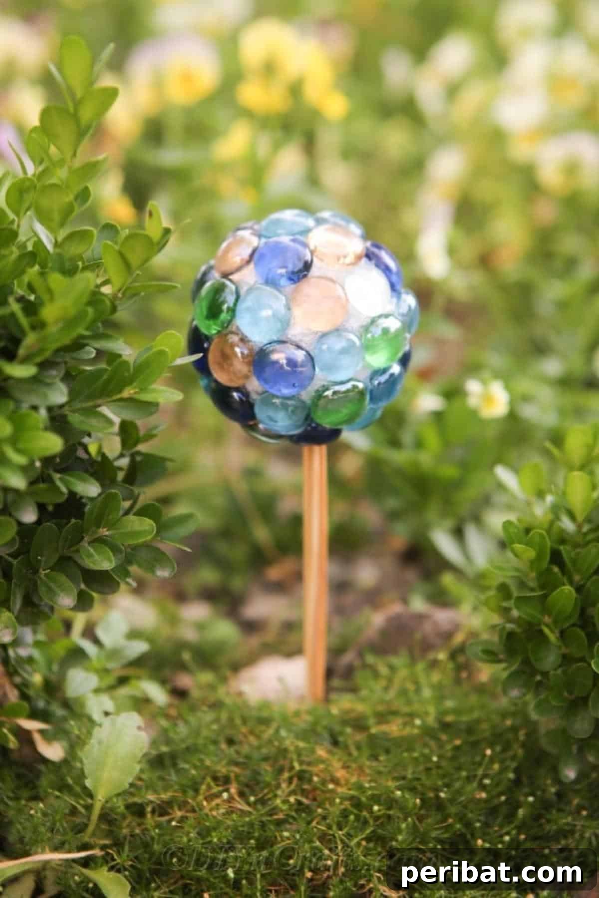 Craft Your Own Garden Spheres 2 A DIY ball ornament stands among plants, shimmering with glass nuggets.