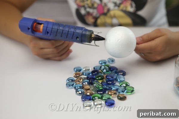 Craft Your Own Garden Spheres 7 Begin gluing glass nuggets to the top of the ball, working in sections.