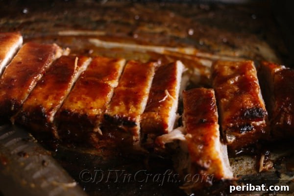 Effortless Fall-Off-The-Bone Oven Ribs 12 BBQ oven baked ribs glistening with glaze on a baking sheet, ready to be broiled