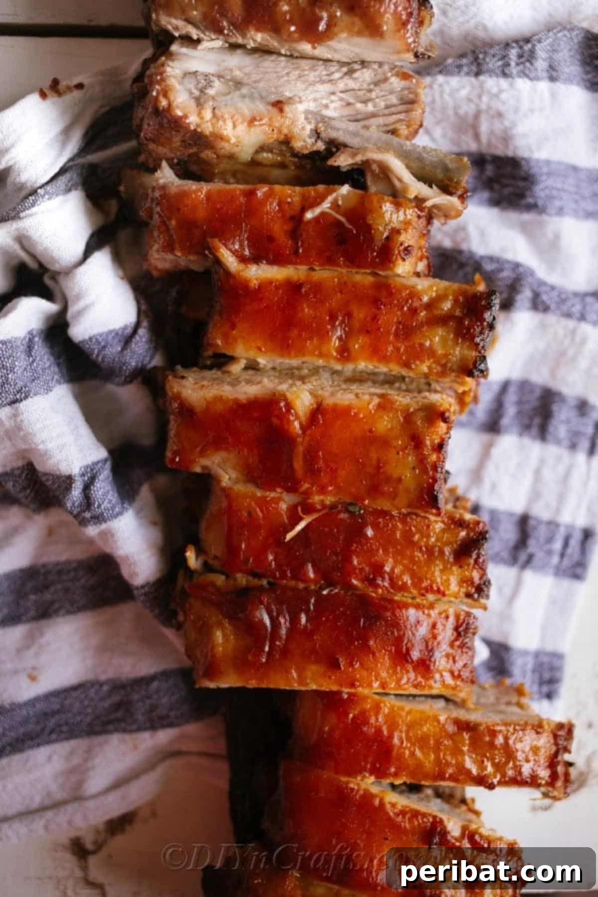 Effortless Fall-Off-The-Bone Oven Ribs 8 A large slab of perfectly oven baked ribs resting on a white and blue striped towel, ready for slicing