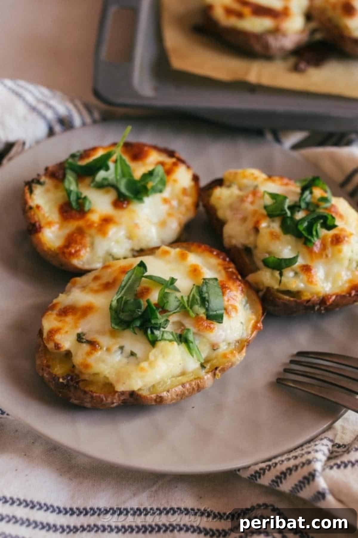 Simple Fully Loaded Potato Skins 4 A beautifully arranged plate featuring three perfectly golden-brown loaded potato skins, each garnished with a sprinkle of fresh green herbs, with a fork poised for enjoyment.