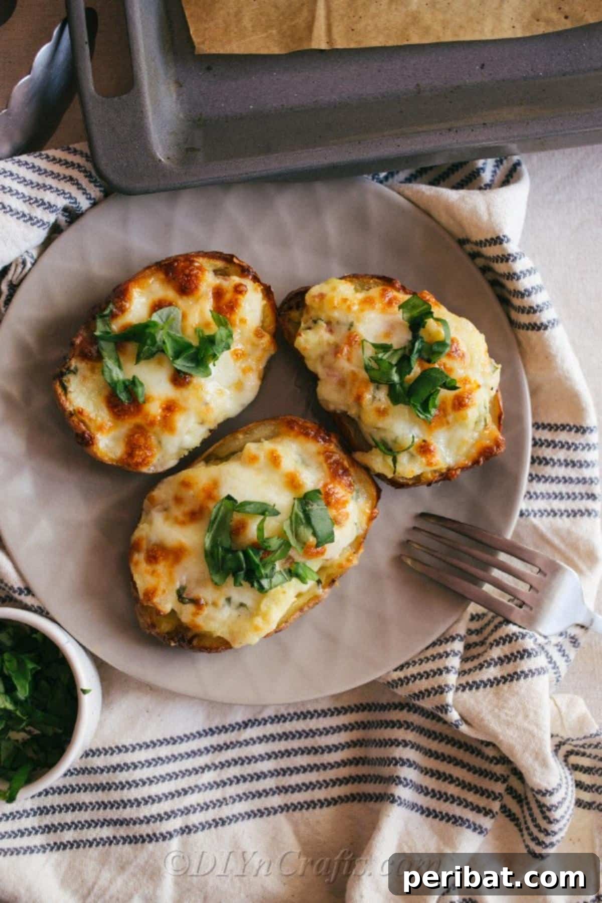 Simple Fully Loaded Potato Skins 6 An inviting overhead shot of loaded potato skins presented on a gray plate, with a fork thoughtfully placed to the side, ready for immediate enjoyment.
