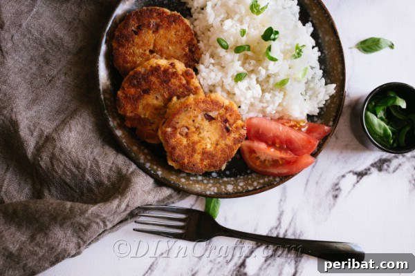 An overhead plate of salmon patties on a dark plate with rice on the side