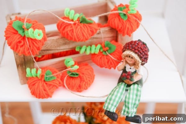 A diy fall decor yarn pumpkin garland displayed on a white shelf with a scarecrow doll