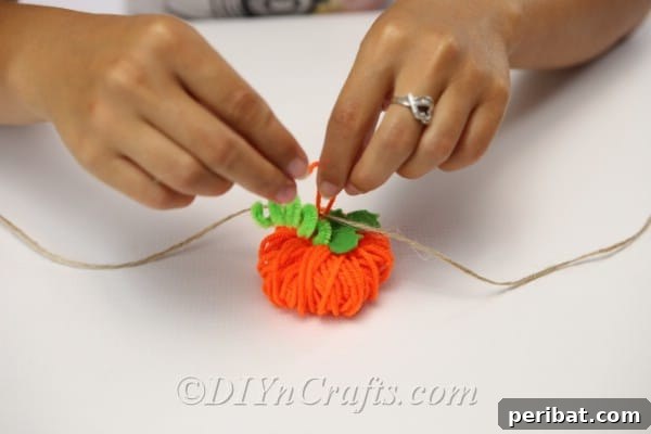 Handmade Autumn Yarn Pumpkin Garland Tutorial 20 Tying the yarn pumpkin to the thread of the diy fall decor garland