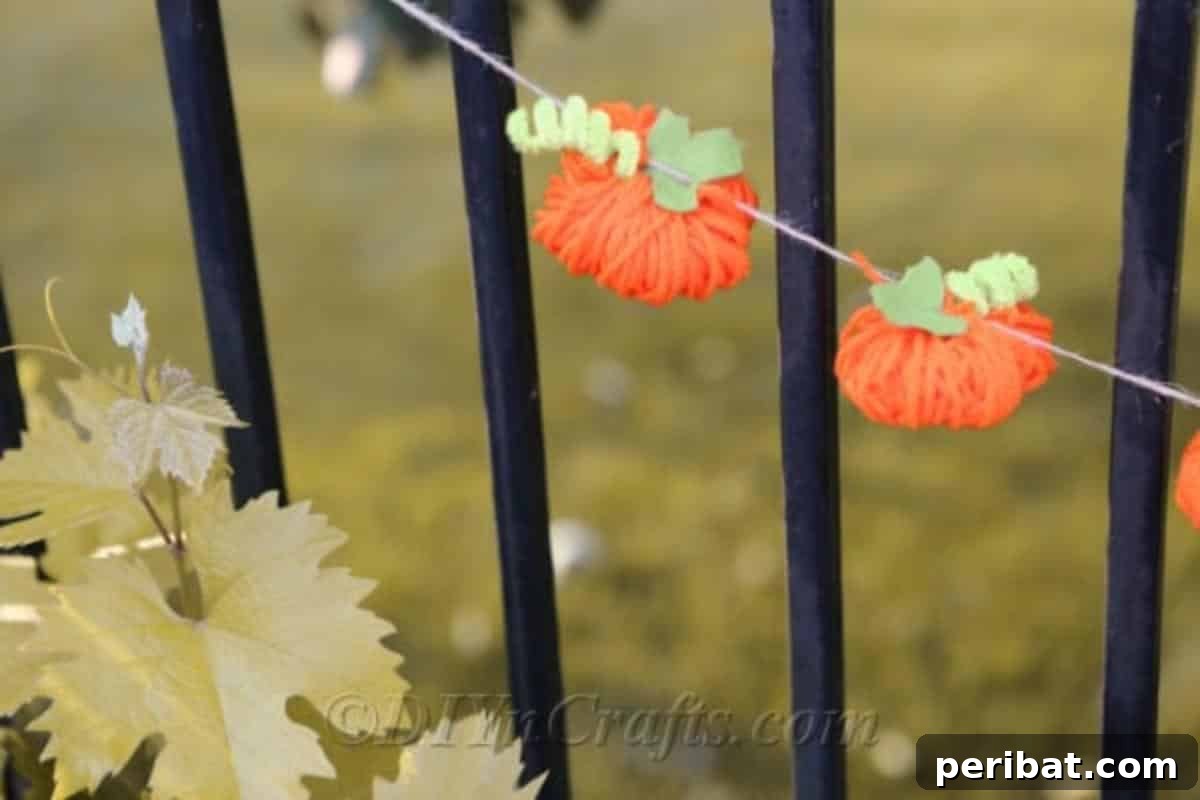 Handmade Autumn Yarn Pumpkin Garland Tutorial 3 Garland featuring on a metal fence.