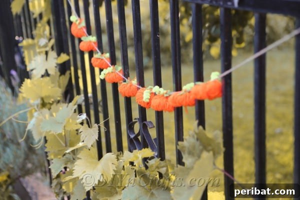 Handmade Autumn Yarn Pumpkin Garland Tutorial 22 The diy fall decor yarn pumpkin garland hanging outside on a black metal fence