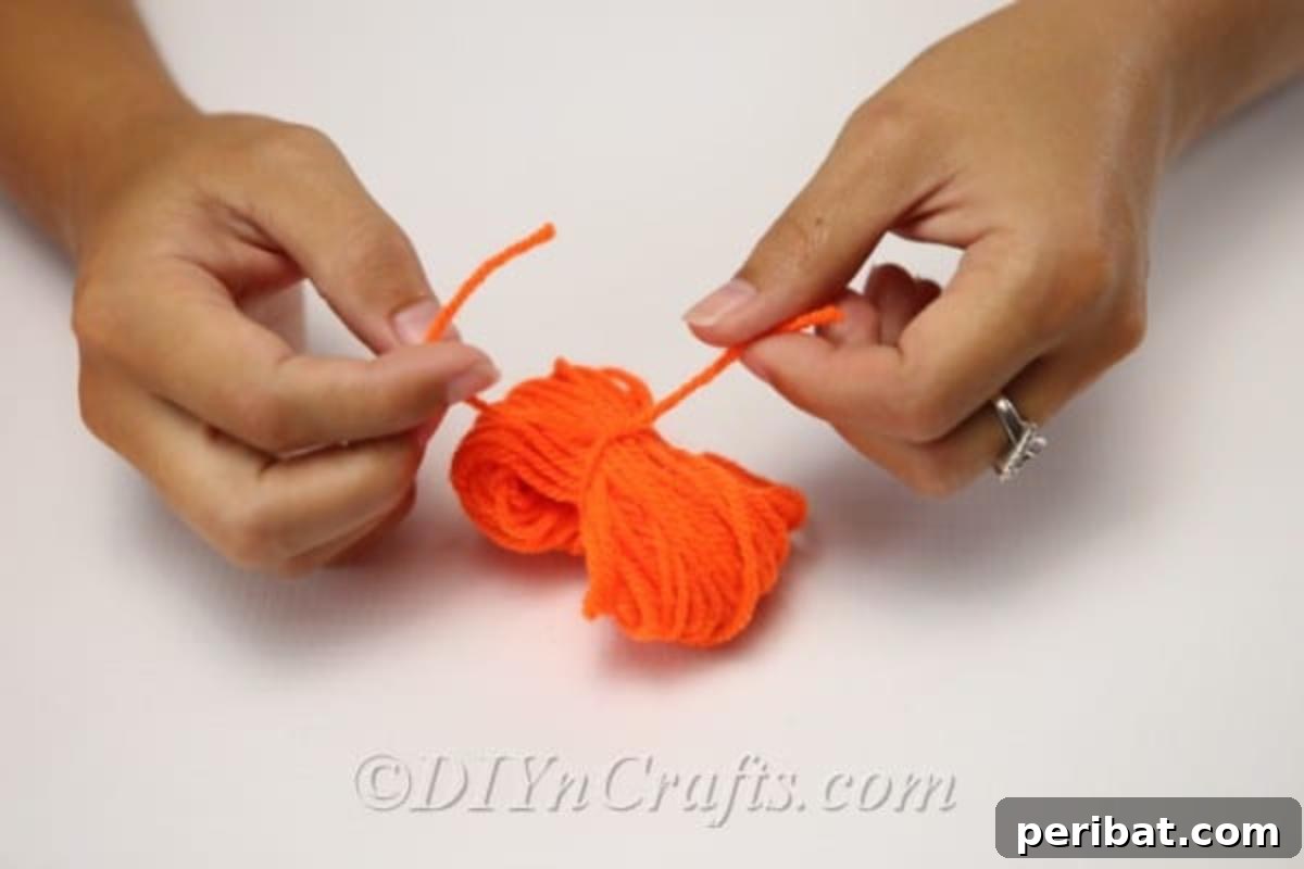 Handmade Autumn Yarn Pumpkin Garland Tutorial 8 A woman tying a yarn pumpkin for the diy fall decor garland