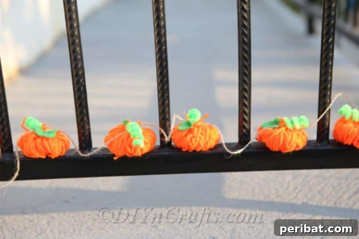 Handmade Autumn Yarn Pumpkin Garland Tutorial 10 A DIY fall decor yarn pumpkin garland displayed outside on a black fence