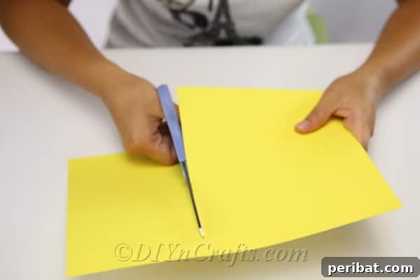 Cutting yellow paper to create core of scarecrow craft body
