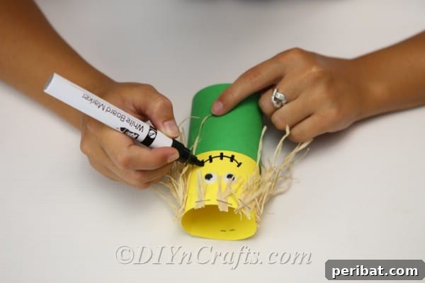 Drawing a face on the paper scarecrow craft with a permanent marker