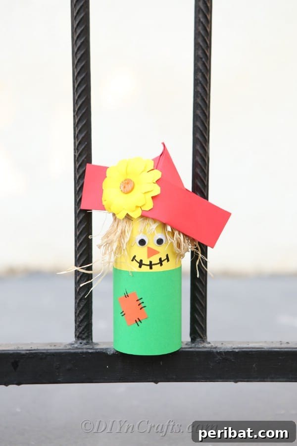 Completed scarecrow paper craft sitting on a black metal fence