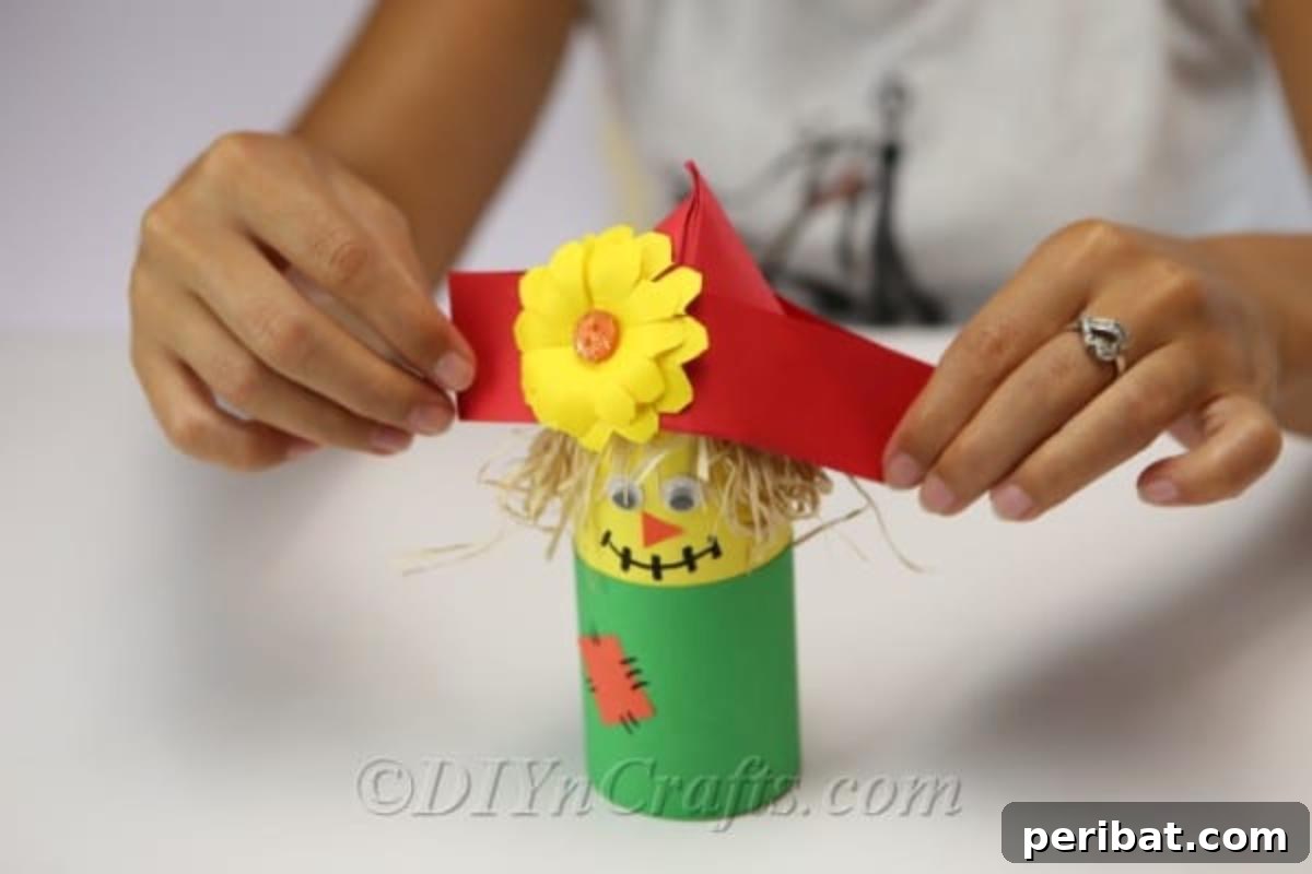 A woman placing the hat on top of the scarecrow paper craft