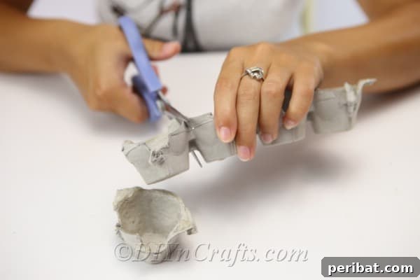 Person cutting apart an egg carton to create individual Halloween monster sections