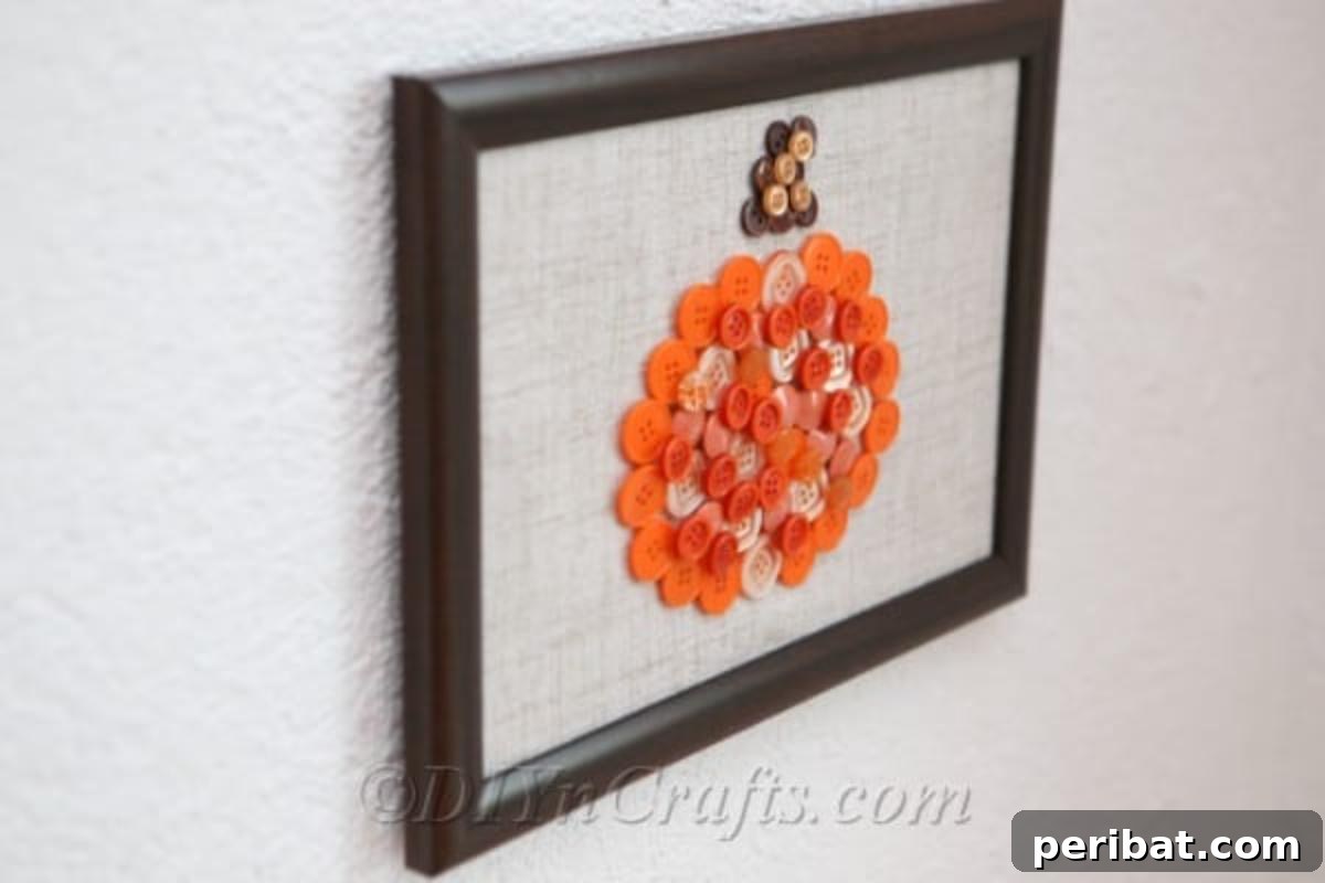 A side view of a charming hanging pumpkin button art wall piece, highlighting its three-dimensional texture