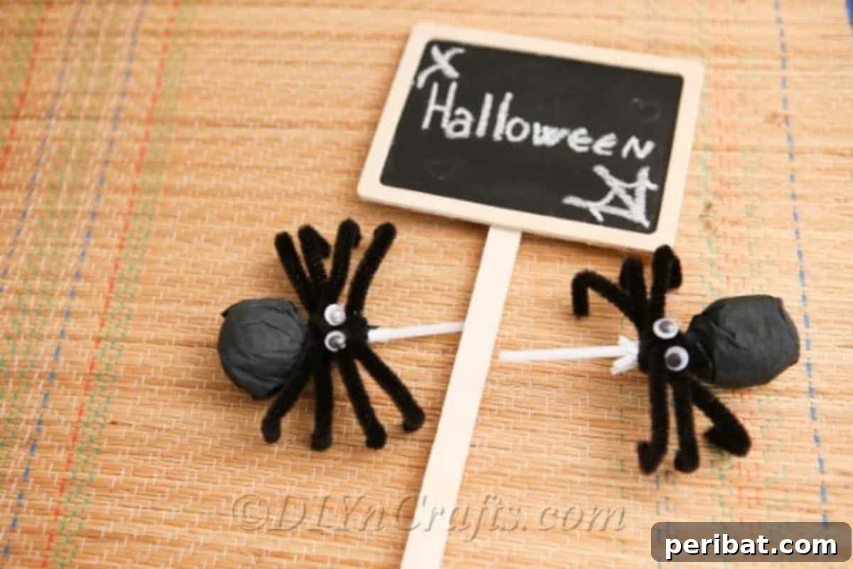 Two completed spider craft lollipops on a table next to a small Halloween decorative sign.