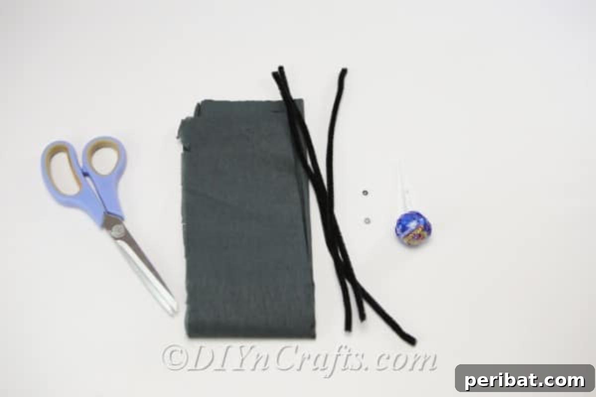 A flat lay of the supplies needed to make a spider craft Halloween lollipop, including lollipops, tissue paper, pipe cleaners, googly eyes, scissors, and a hot glue gun.