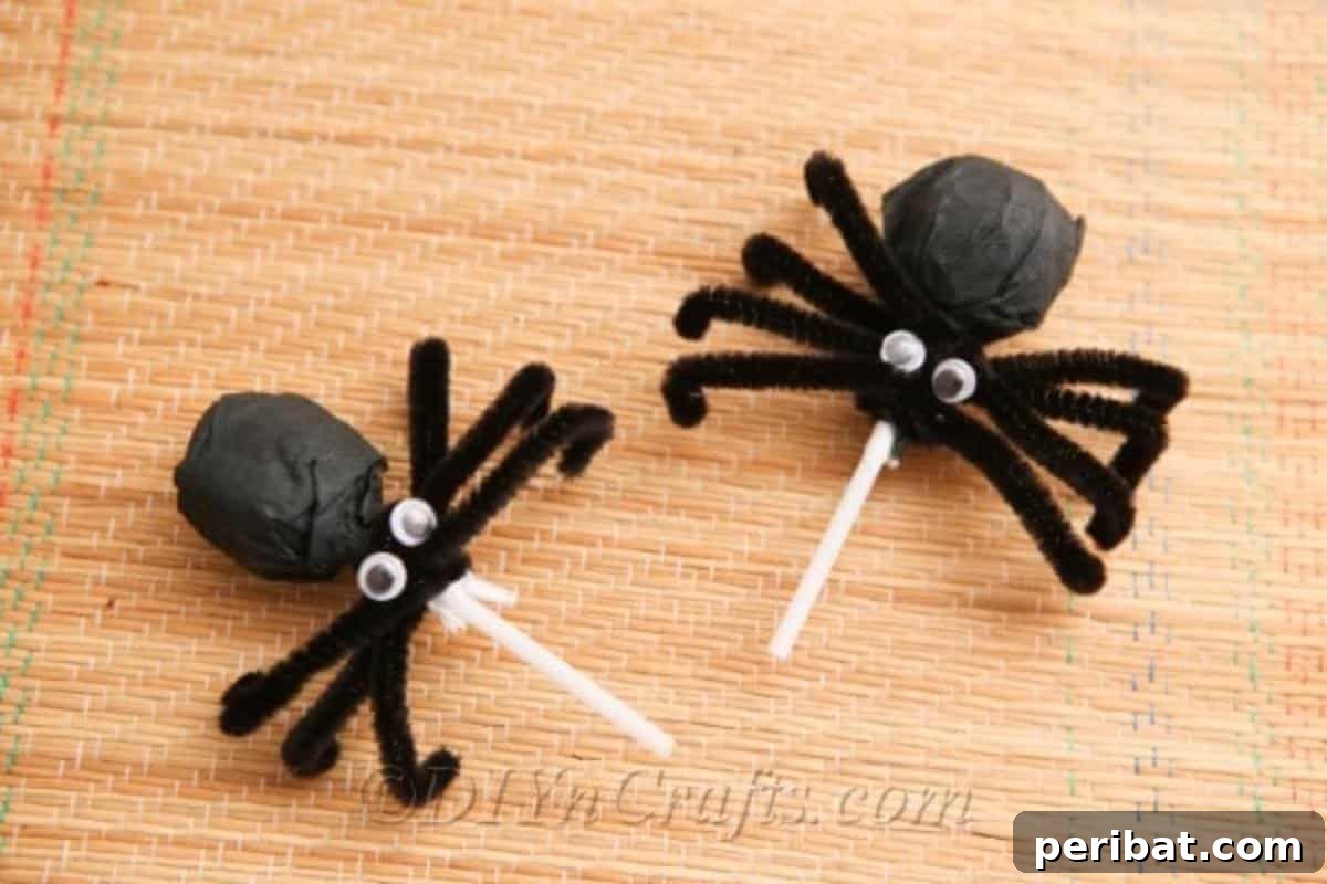 A close-up of an adorable completed spider lollipop for Halloween, showing the googly eyes and pipe cleaner legs.