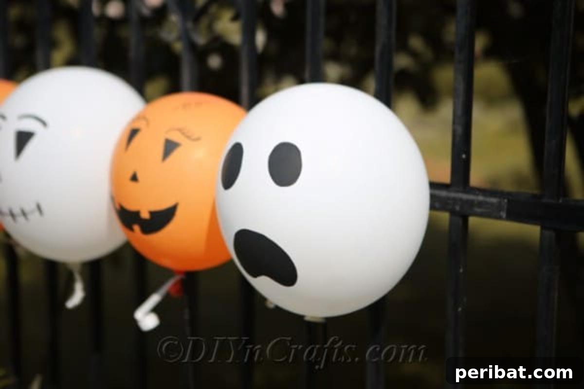 DIY Frightfully Fun Halloween Balloons 3 Assorted DIY Halloween balloons tied to a rustic black metal fence, showcasing ghost and jack-o'-lantern designs.