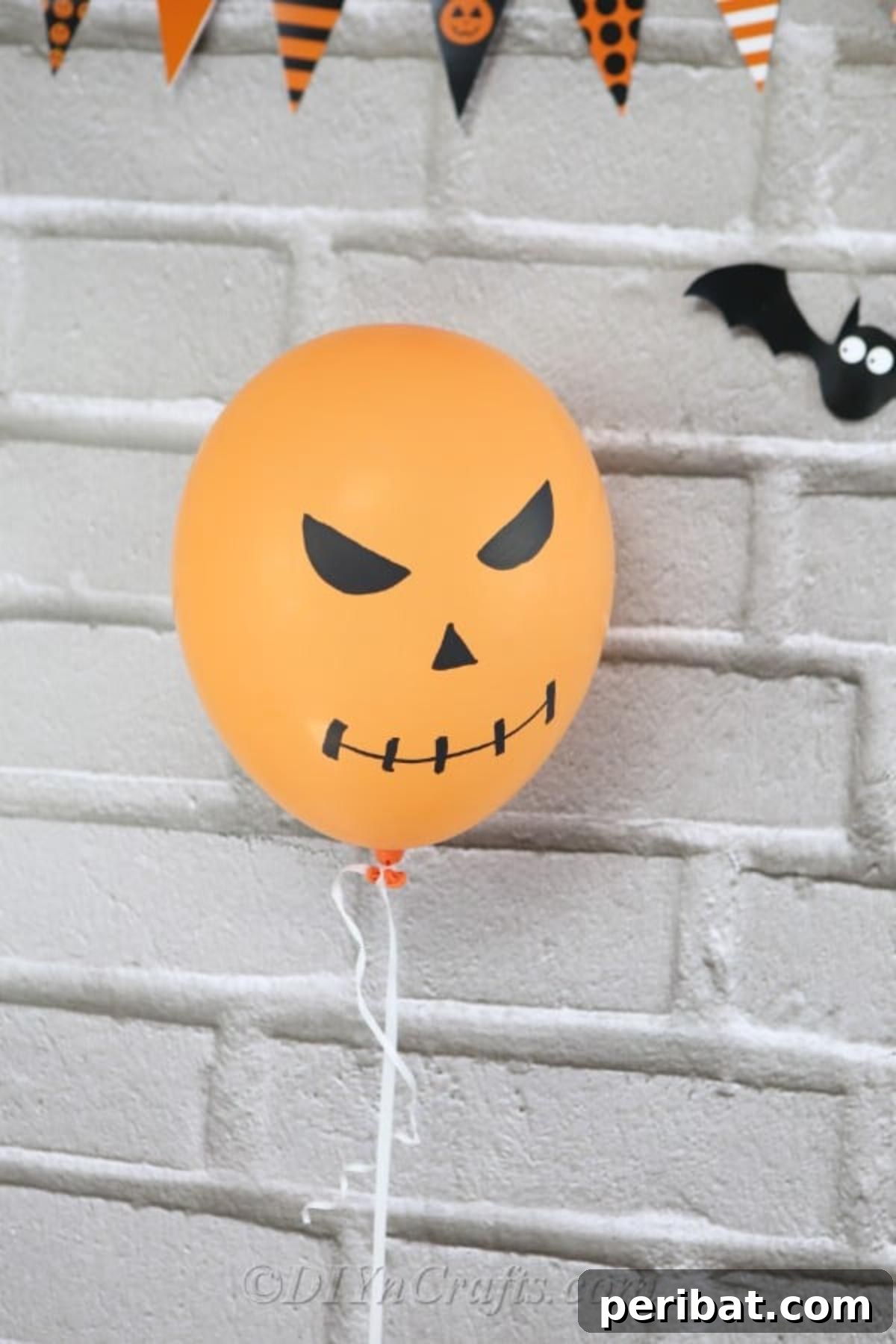 DIY Frightfully Fun Halloween Balloons 4 A creative DIY orange jack-o'-lantern Halloween balloon hanging against a textured brick wall, adding a festive touch.