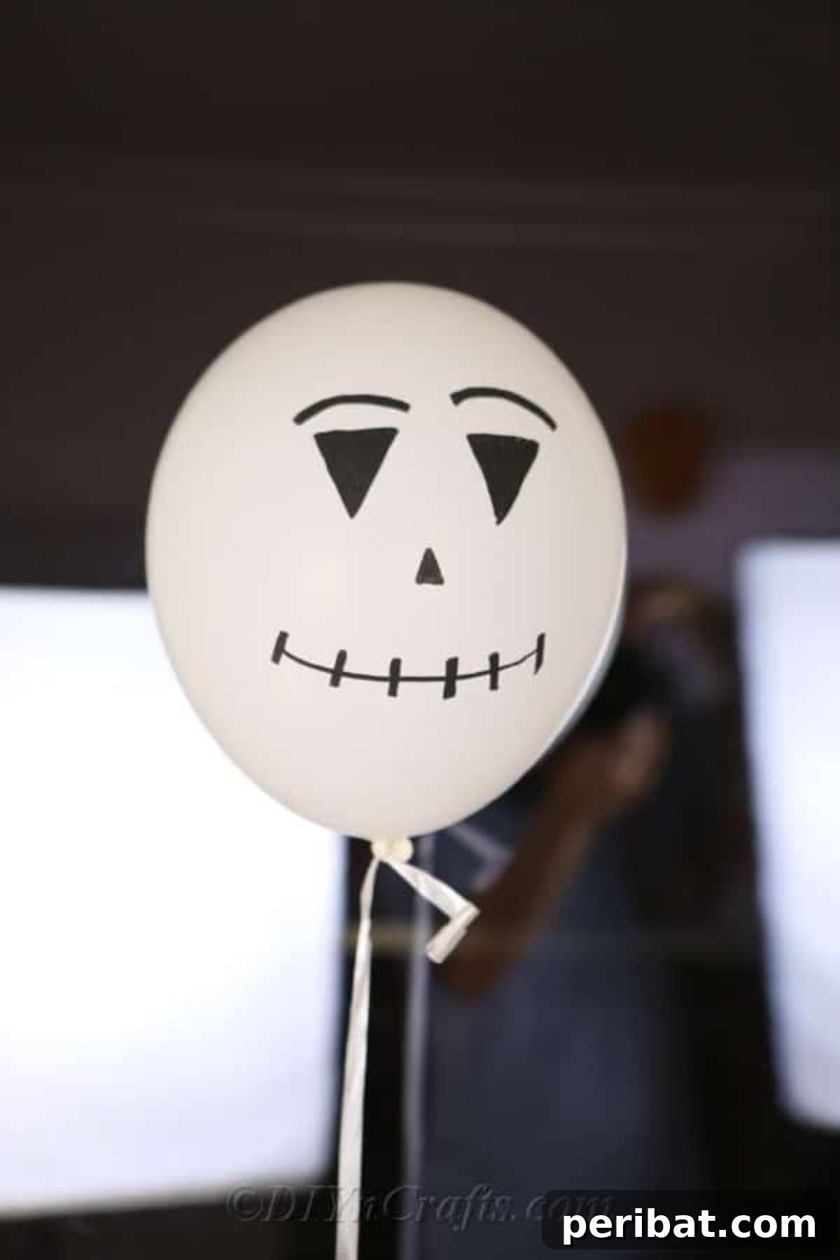 DIY Frightfully Fun Halloween Balloons 5 A charming white scarecrow or ghost Halloween balloon design positioned against a window, showcasing detailed marker work.