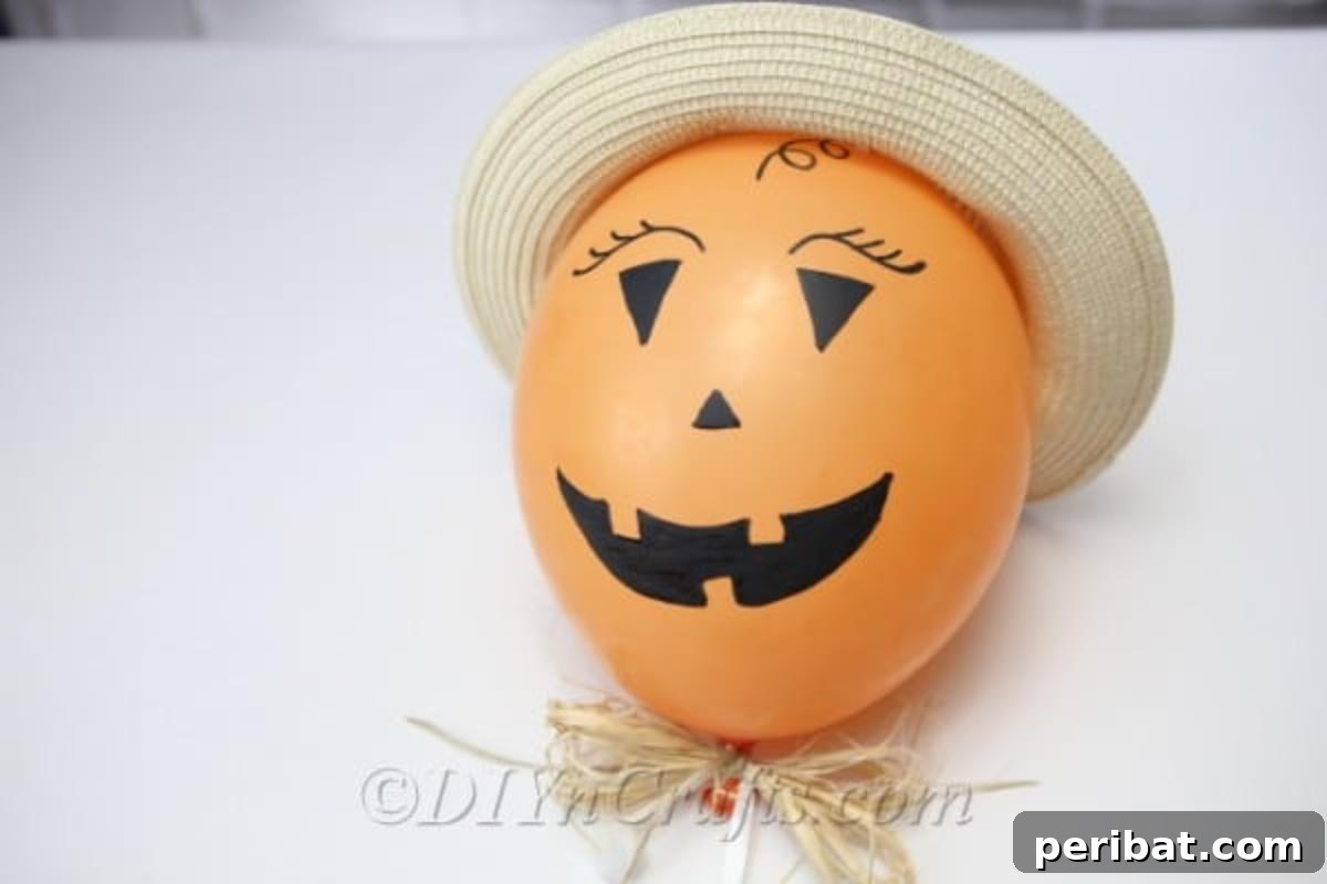 DIY Frightfully Fun Halloween Balloons 6 A charming scarecrow Halloween balloon design, complete with a straw hat, laying casually on a wooden table.