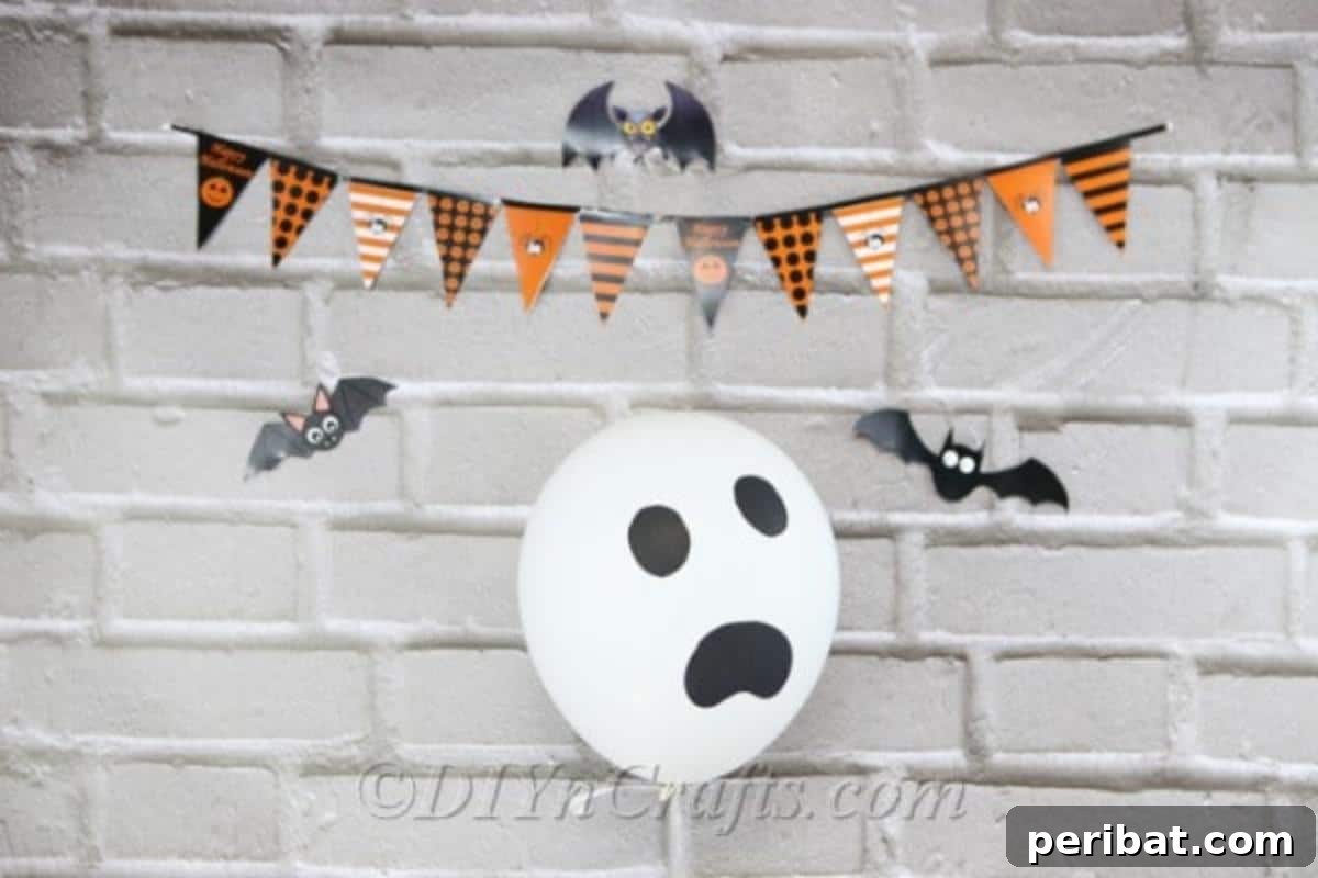 DIY Frightfully Fun Halloween Balloons 9 A ghostly Halloween balloon decoration featuring a classic spooky face, hanging against a gray brick wall with a festive Halloween banner above.